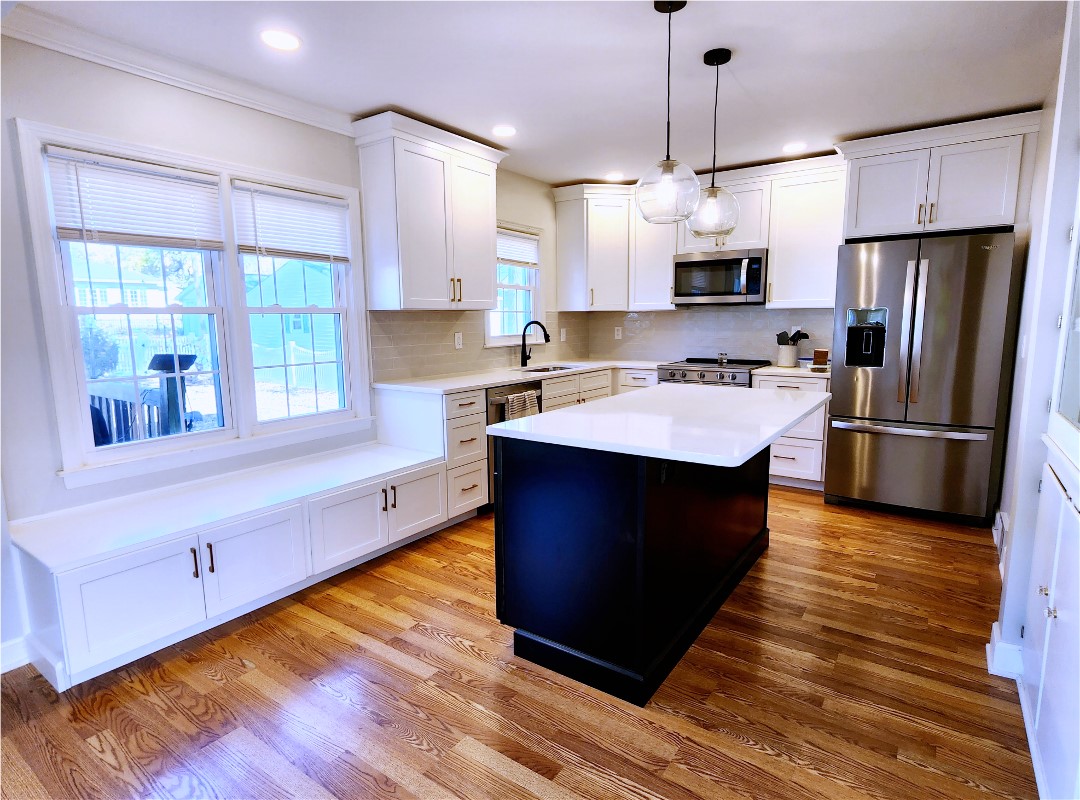 A kitchen with white cabinets and black island.