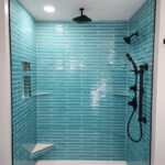 A bathroom with blue tile and black fixtures.