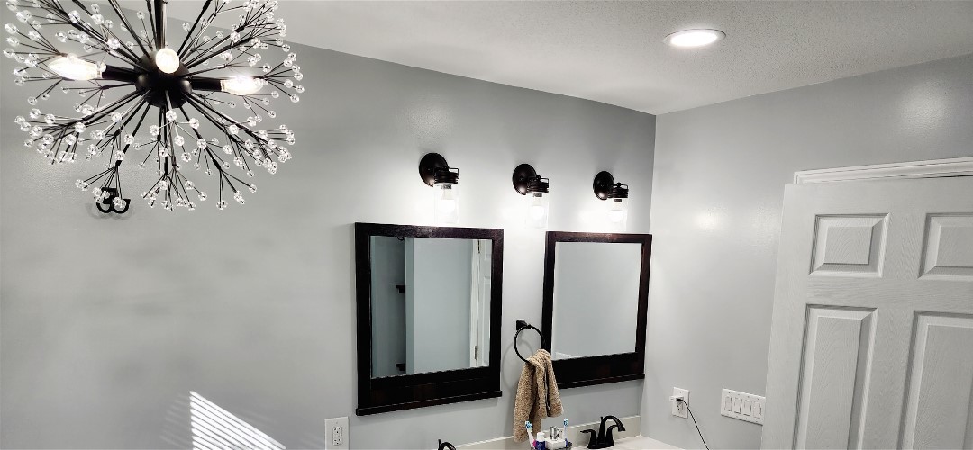 A bathroom with two mirrors and lights on the wall.