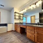 A bathroom with wooden cabinets and floors, a tub and sink.