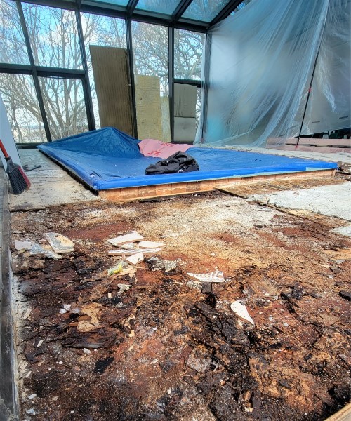 A room with a blue mat and some debris on the floor.