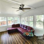 A living room with a large window and a ceiling fan.