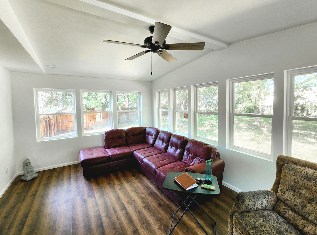 A living room with a large window and a ceiling fan.