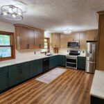 A kitchen with green cabinets and hardwood floors.