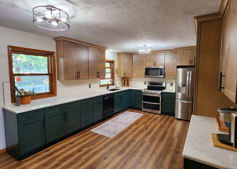 A kitchen with green cabinets and hardwood floors.